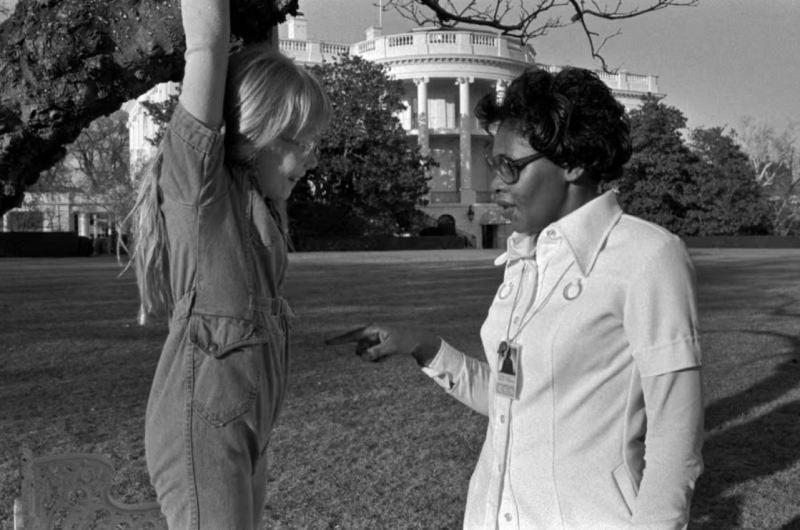 23 February 1977: Amy Carter hanging from a tree as she speaks with her nanny Mary Fitzpatrick on the south lawn of the White House in Washington
