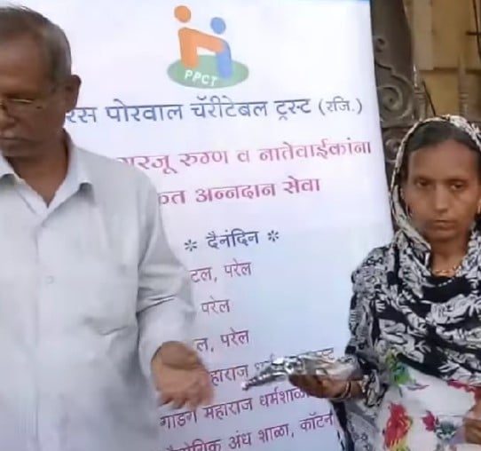 A man distributing food pakages to poor people under the Paras Porwal Charitable Trust