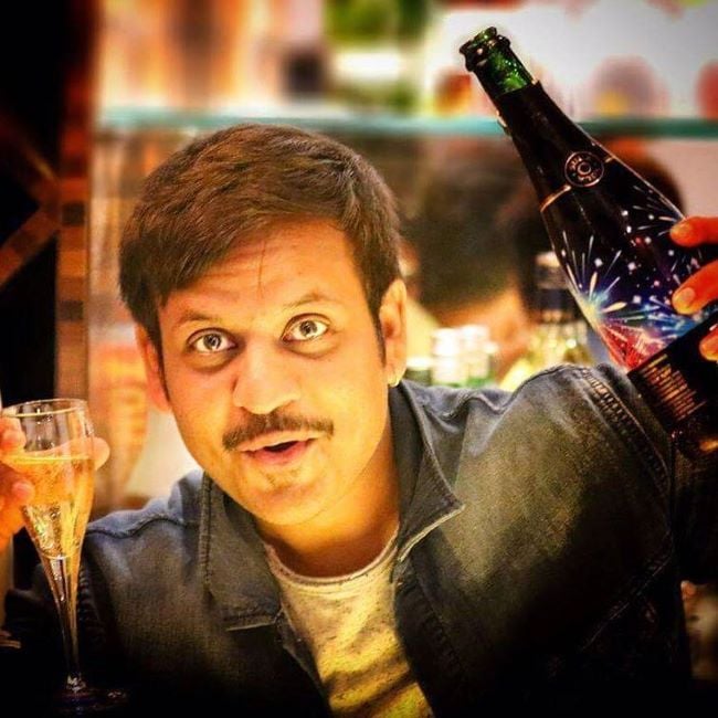 Akul Balaji holding a glass and a bottle of champagne