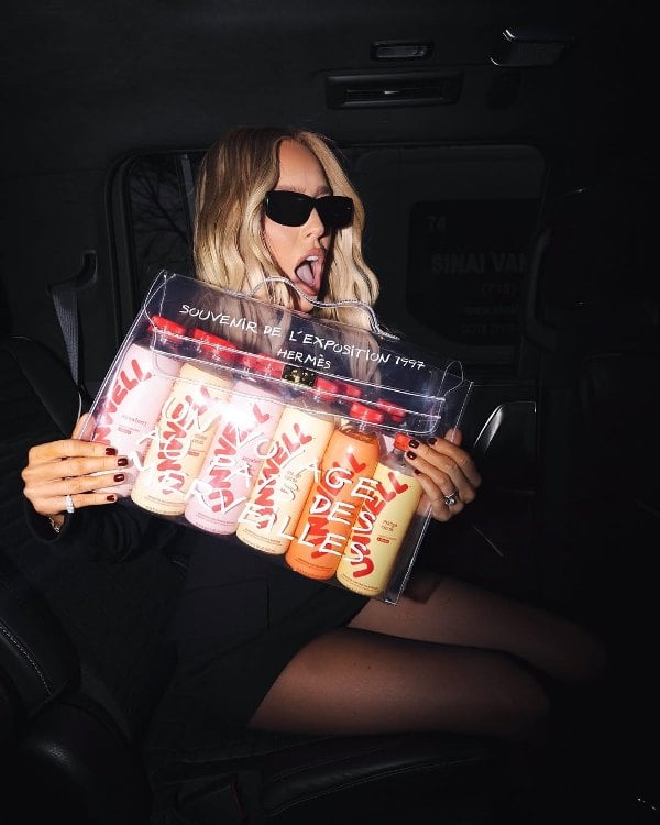 Alexandra Cooper, while holding a pack of Unwell Hydration bottles