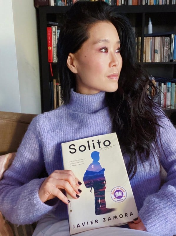 Alicia Hannah-Kim, while sitting in her library holding a book 