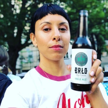 Anisa Qureshi posing with a bottle of an alcoholic beverage