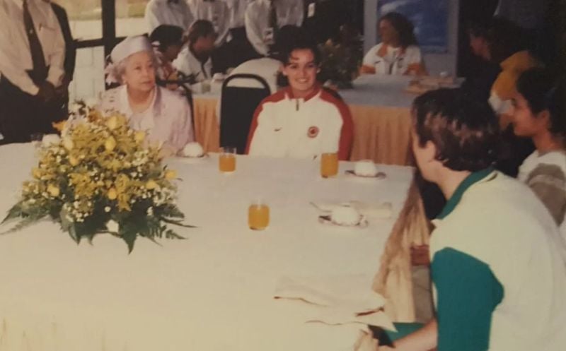 Aparna Popat sitting with Queen Elizabeth II and others.