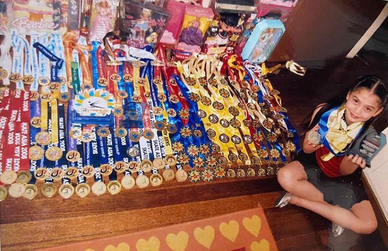 Ashley Ortega displaying her various medals, awards, and her collection of Barbie dolls