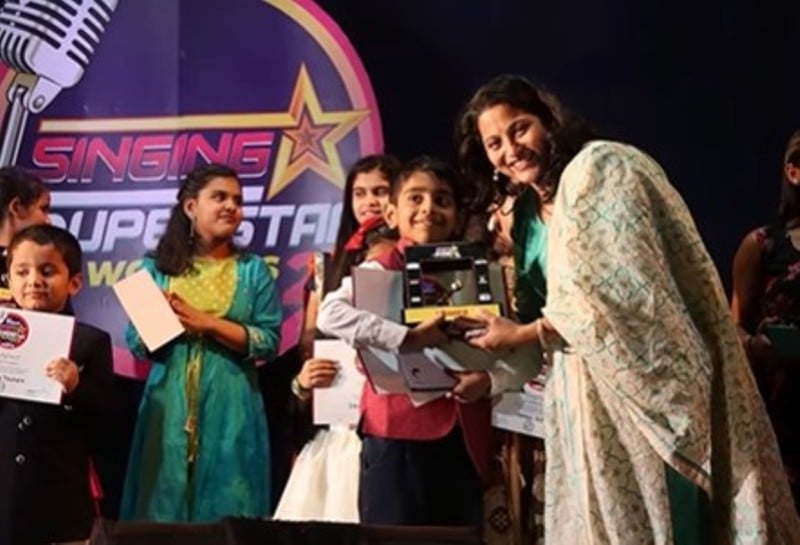 Atharva Bakshi receiving an award for a singing competition at his school