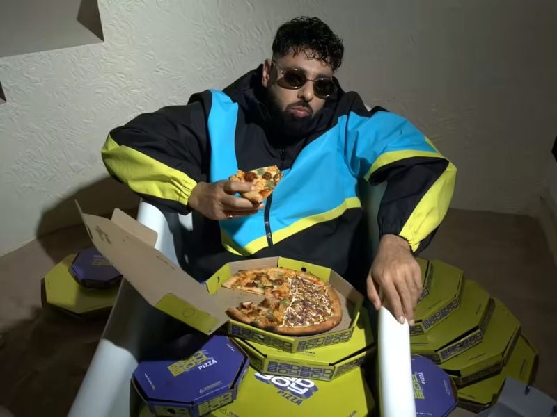 Badshah posing for a photo with the Pizza from his Pizza outlet