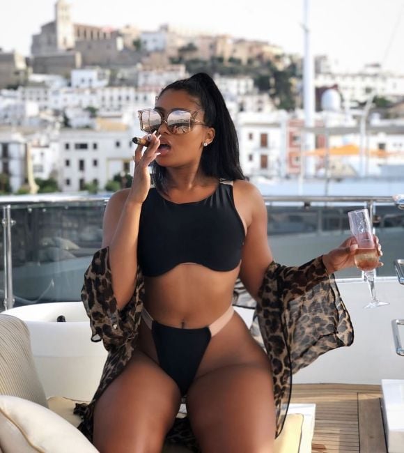 Brit Eady smoking a cigar while holding a glass of alcohol