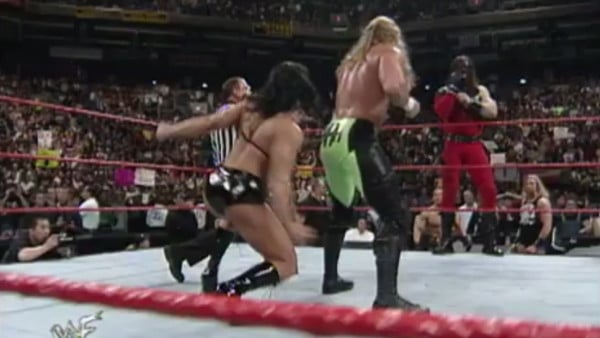 Chyna performing a low blow on Triple H while Kane distracted him