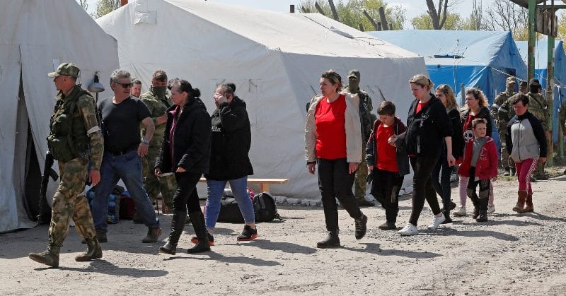 Civilians being escorted by armed soldiers in a camp set up by the United Nations (UN) in Ukraine