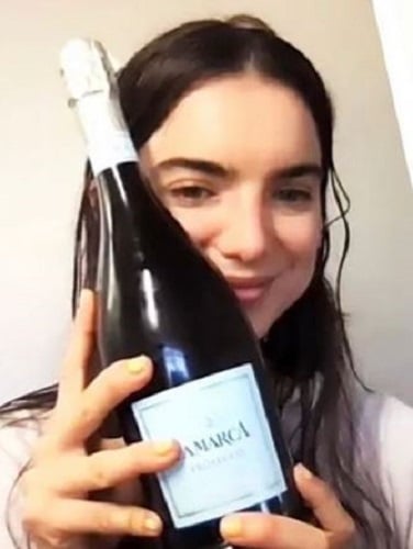 Dylan Gelula holding a bottle of wine