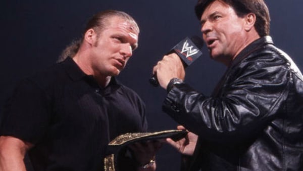Eric Bischoff handing over the WWE Championship belt to Triple H at an event