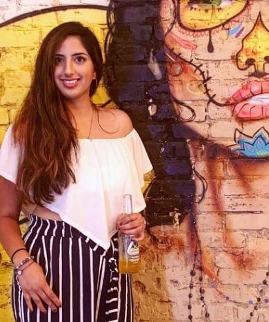 Esha Verma posing with a bottle of beer