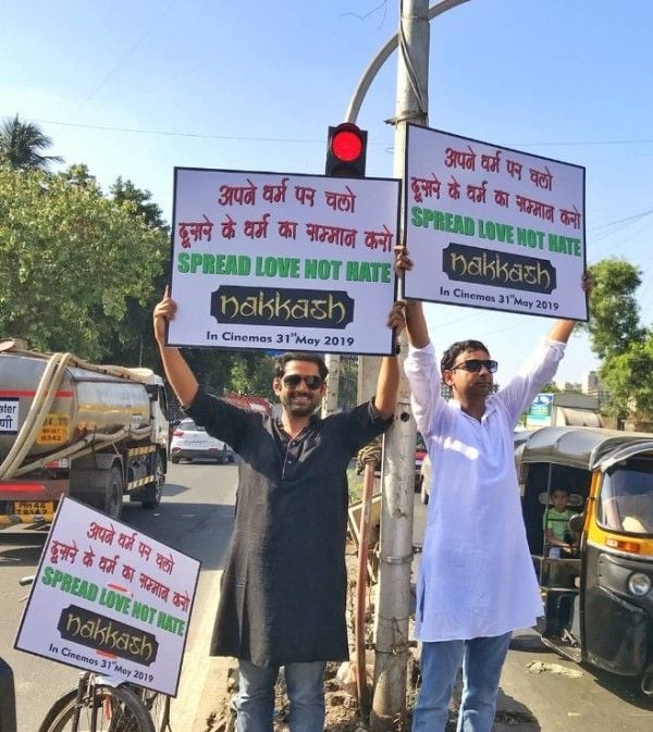 Inaamulhaq standing on road along with his co-star Sharib Hashmi, holding the hoardings, for the promotion of his film 