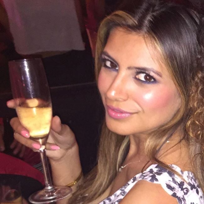 Jasveen Sangha holding a glass of alcohol