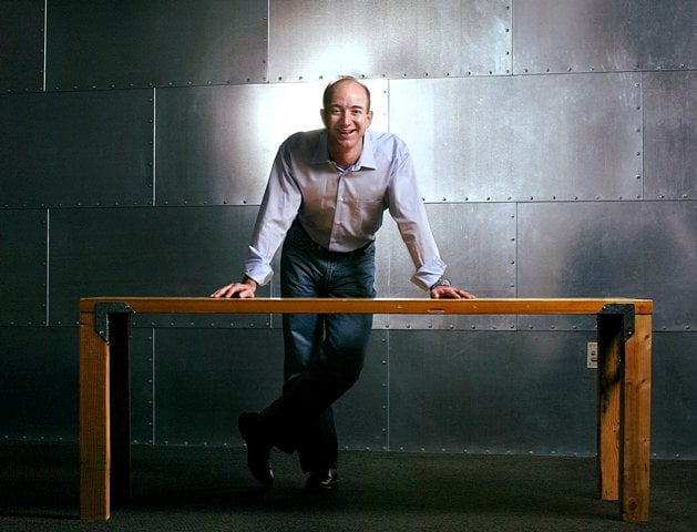 Jeff Bezos posing with the table that he had made from a door