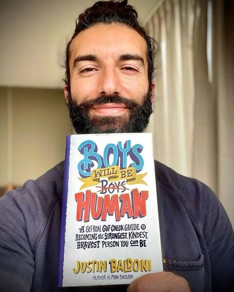 Justin Baldoni posing with his book titled 