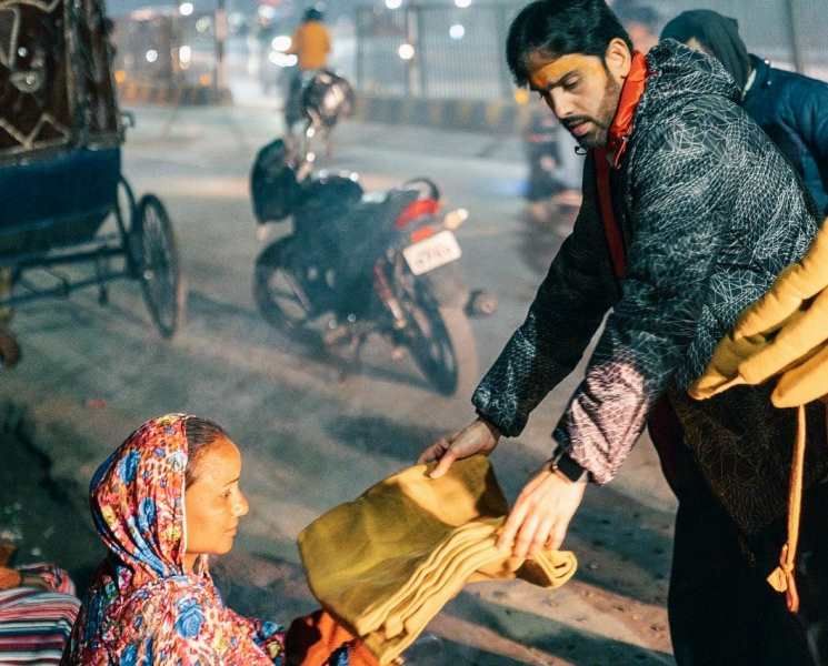Luv Sinha (right) distributing blankets to poor people
