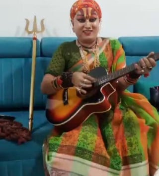 Mahamandaleshwar Hemangi Sakhi while playing a guitar