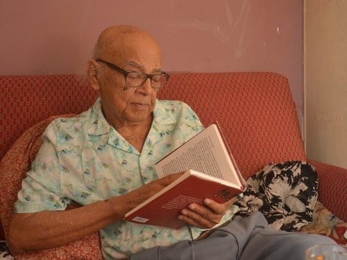 Manoj Mitra reading a book