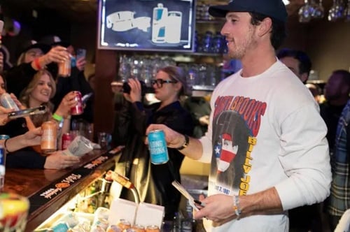 Miles Teller holding a can of alcohol