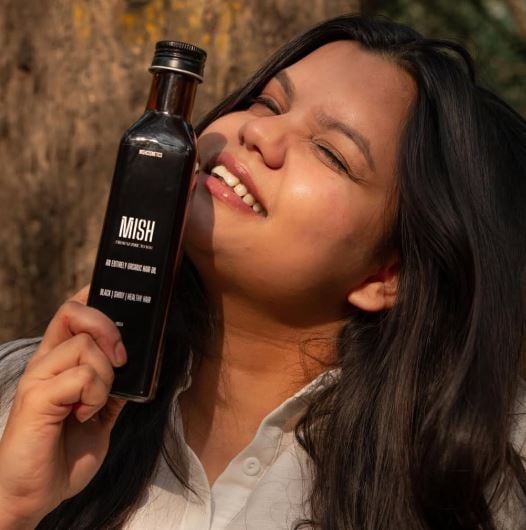 Misha Agrawal holding a bottle of Mish Hair Oil