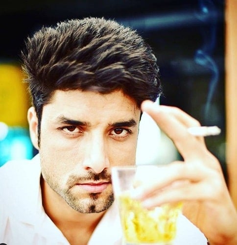Nitin Chauhaan holding a cigarette and glass of alcohol