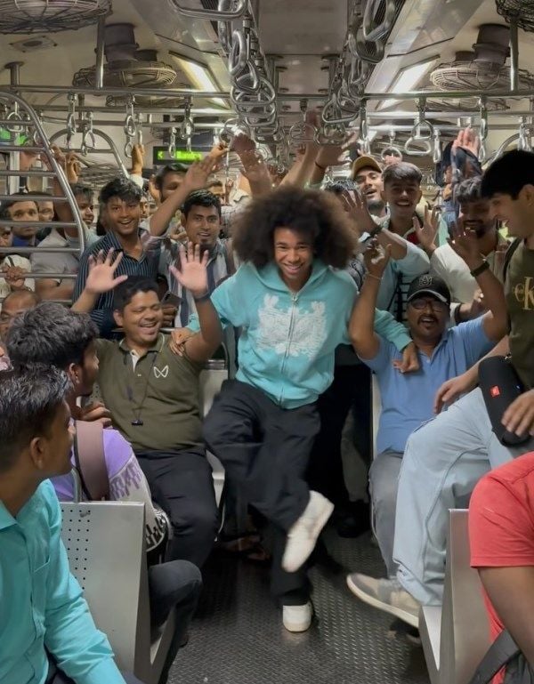 Noel Robinson (in light blue hoodie) vibing with Indian people in a local train