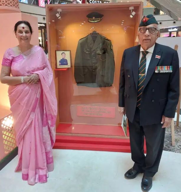 Parents of Vijayant Thapar standing next to the uniform of their son displayed at the DLF mall in Noida