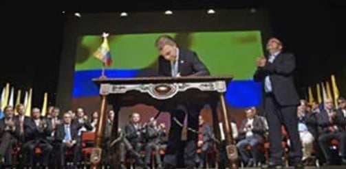 President Santos signs the Final Peace Agreement while the FARC’s top leader, Rodrigo Londoño, aka. Timochenko, is standing by his side