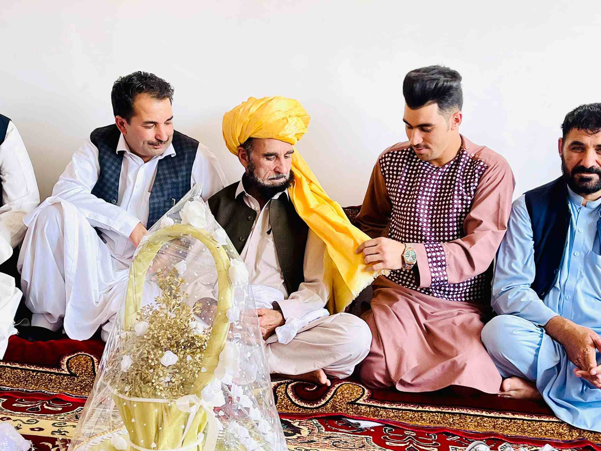 Rahmanullah Gurbaz (second from right) tying turban on his father