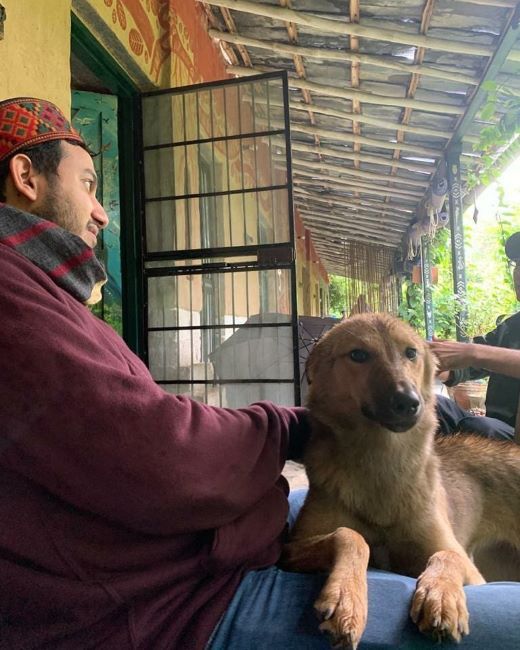 Ritesh Agarwal posing for a photo with a dog on his lap during his trip to Himachal Pradesh