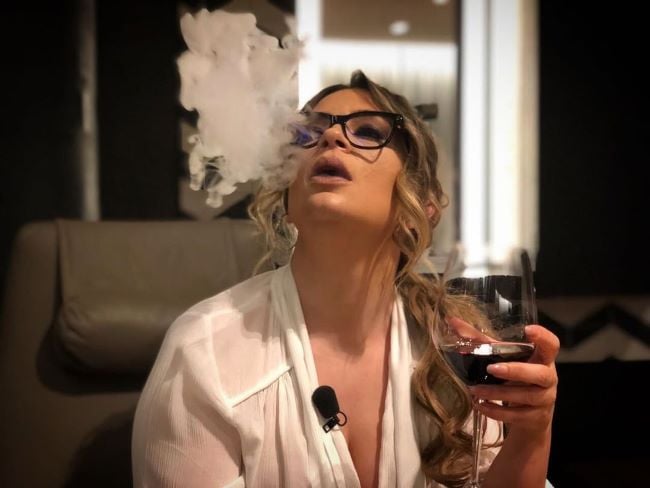 Rozana Radi smoking and holding a glass of wine