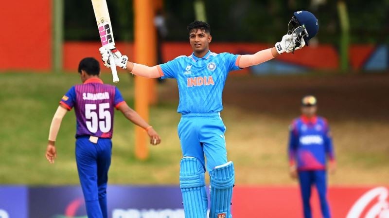 Sachin Dhas raising his bat and helmet to celebrate his century during the Super Six match against Nepal at Mangaung Oval