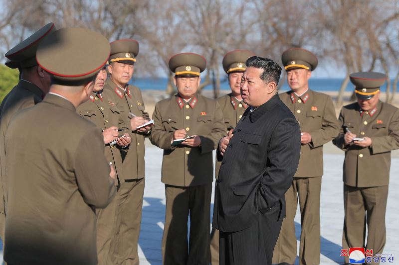 Senior military officers stand around Kim taking notes as he passes instructions