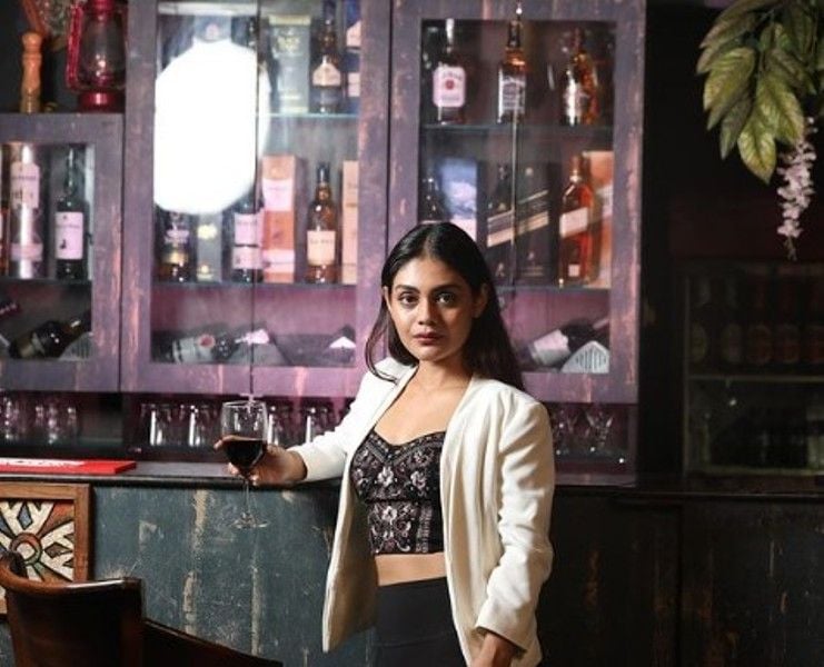 Sreejita De holding a glass of wine