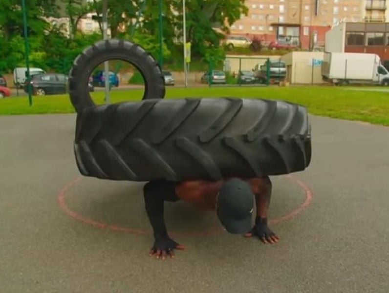 The Lyon Black performing push-ups with a heavy tyre on his back